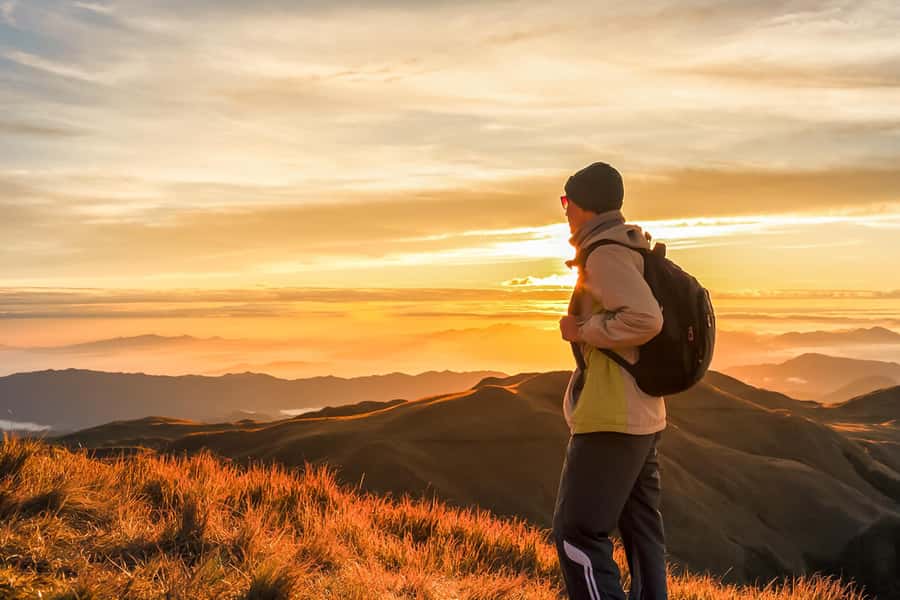 A hiker on the rim of Mount Batur as the sun comes up over Bali